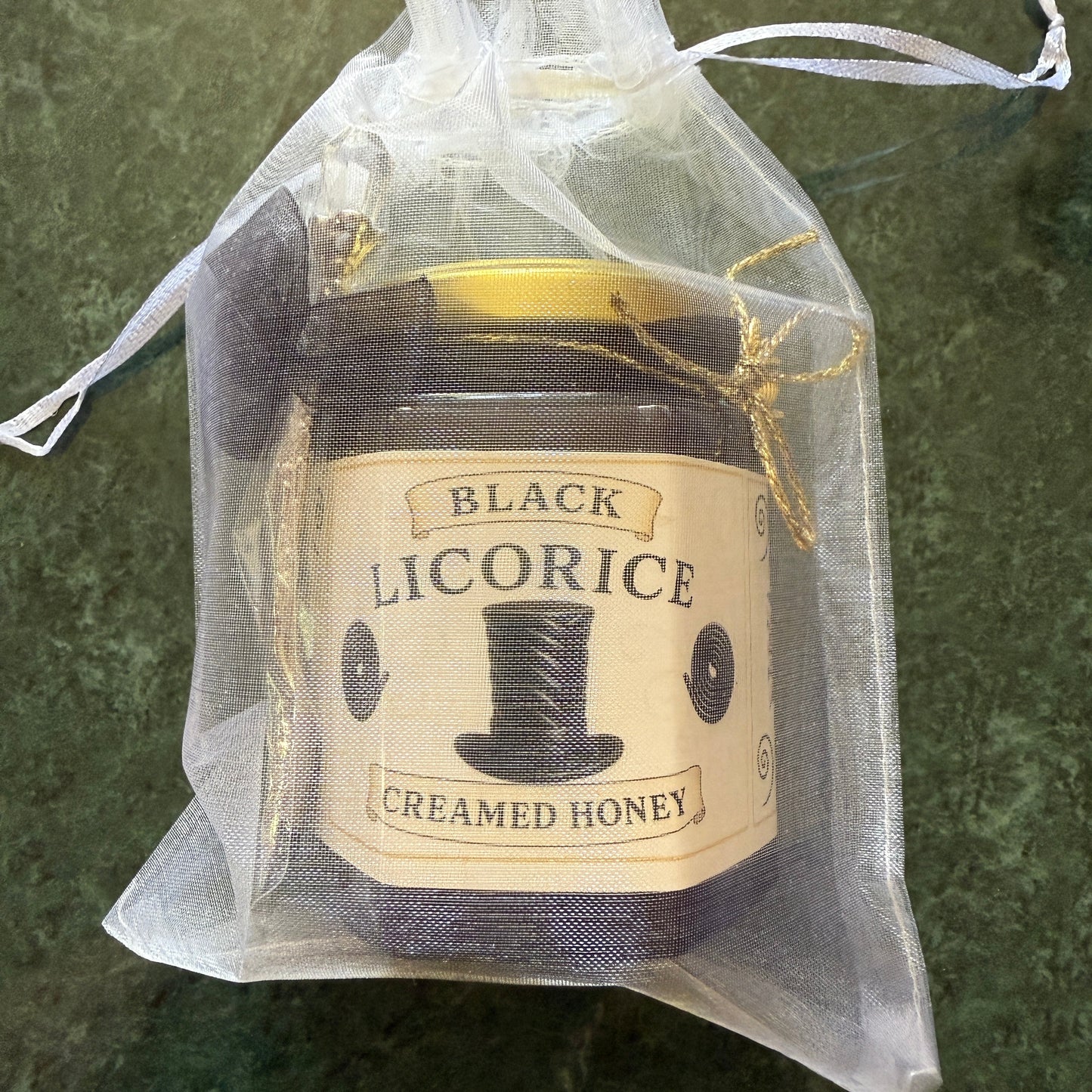 Flat lay of licorice honey jar, gold spoon, and packaging accents—luxury gift for licorice fans.