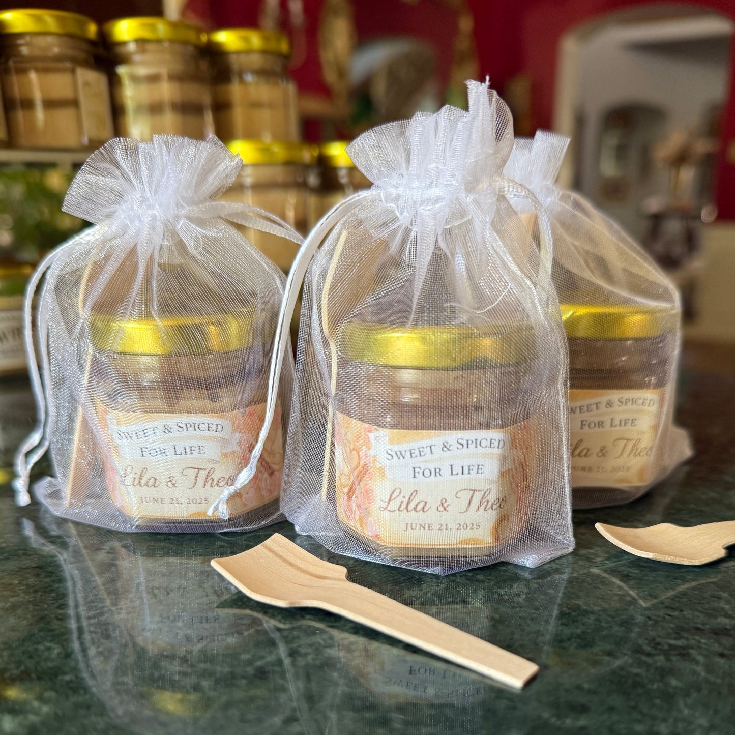 Handcrafted edible wedding favors with cinnamon creamed honey and personalized labels, displayed on marble surface.