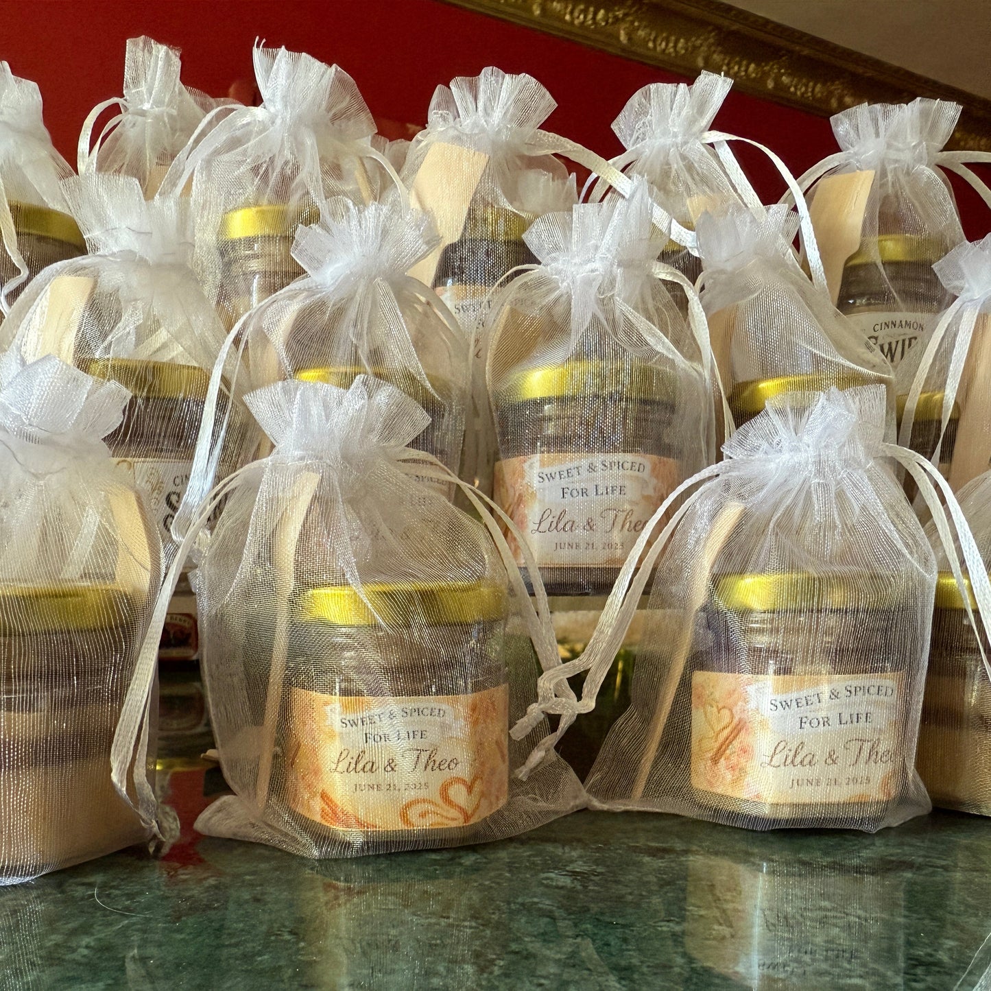 Wedding favor jars with cinnamon honey styled in sheer organza bags and gold spoons, ready for guest gifting