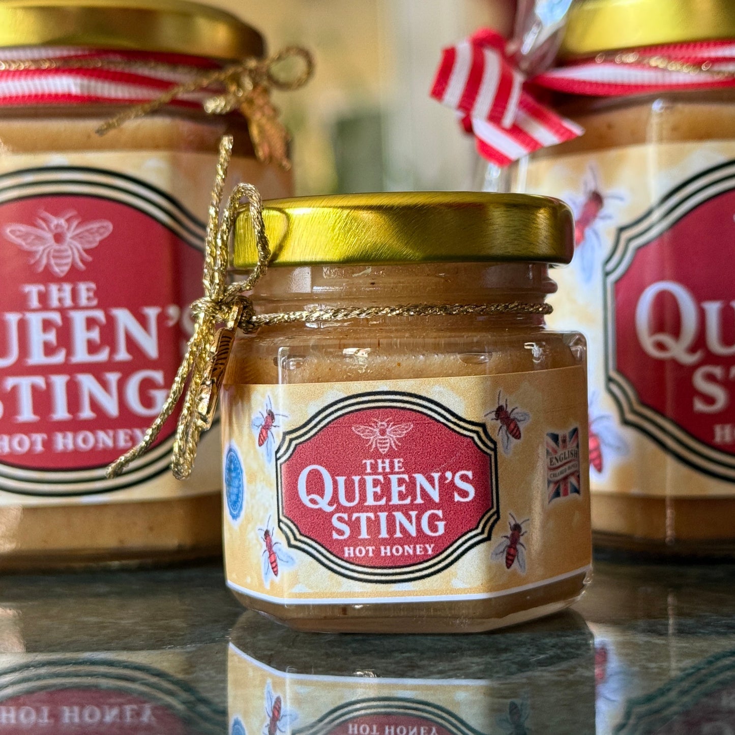 Gift-ready hot honey in glass jar labeled The Queen’s Sting, perfect for foodies